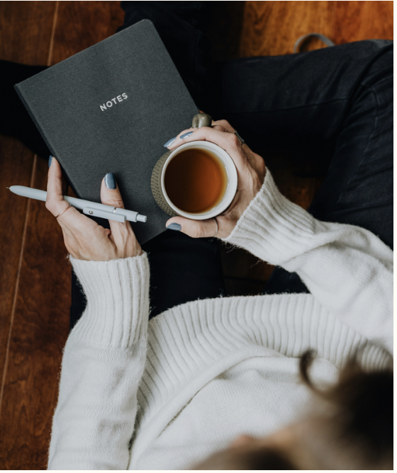 Person journaling with a cup of tea
