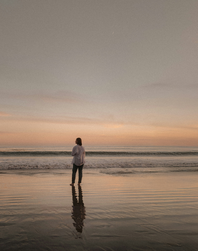 Person standing on a beach at sunset