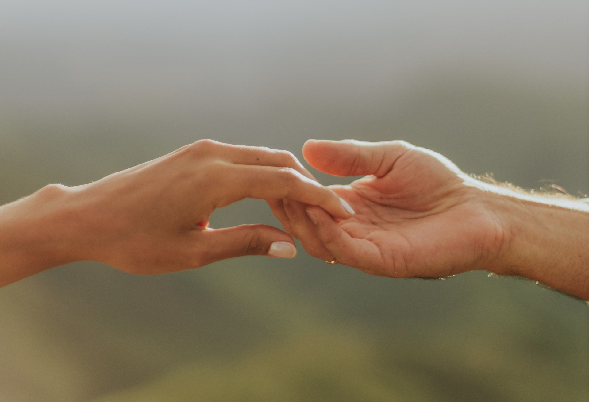 Two hands reaching toward each other in warm golden light