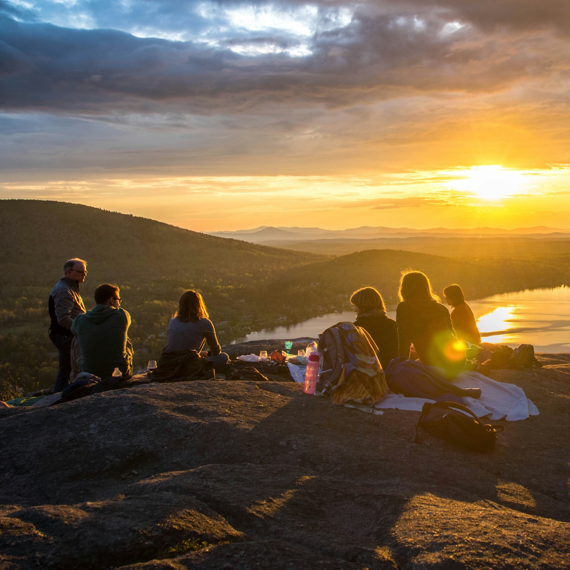 Group of people watching a sunset over a lake and mountains